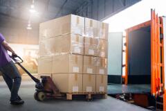 Worker hauling large boxes in warehouse